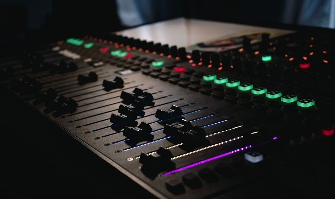 Close-up of an audio mixing console with illuminated faders and controls