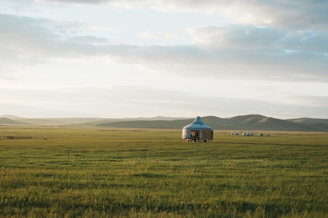 Yurt standing in a wide grassland beneath cloud-filled skies