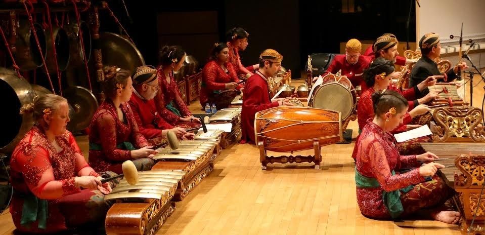 Gamelan ensemble performing together on metallophones and drums
