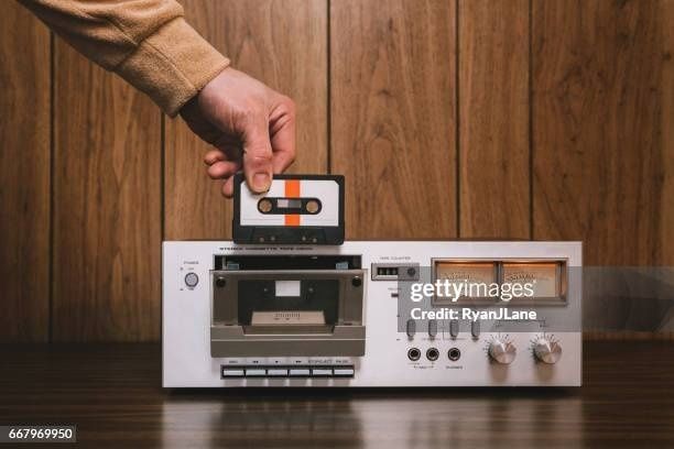 Hand holding a cassette tape above a vintage stereo deck