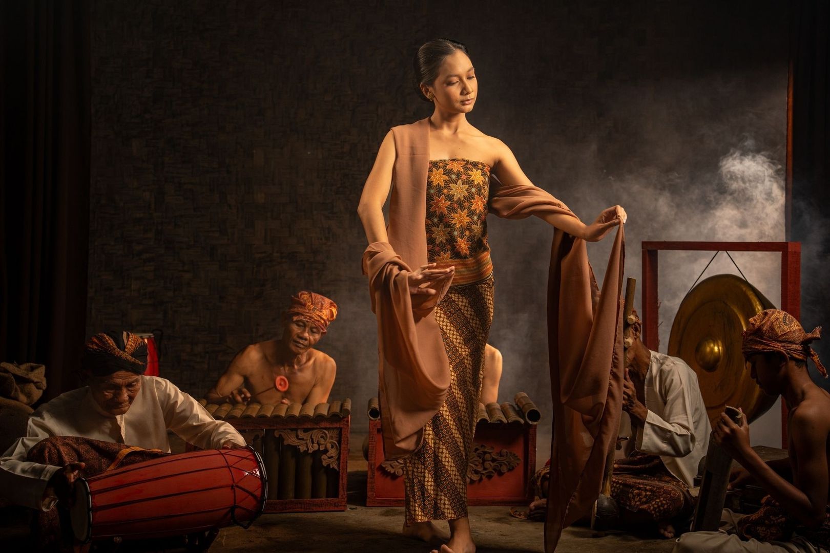 Gamelan musicians perform around a dancer in traditional Indonesian dress